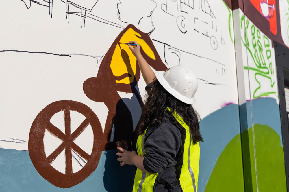 one of the student volunteers panting a portion of mural